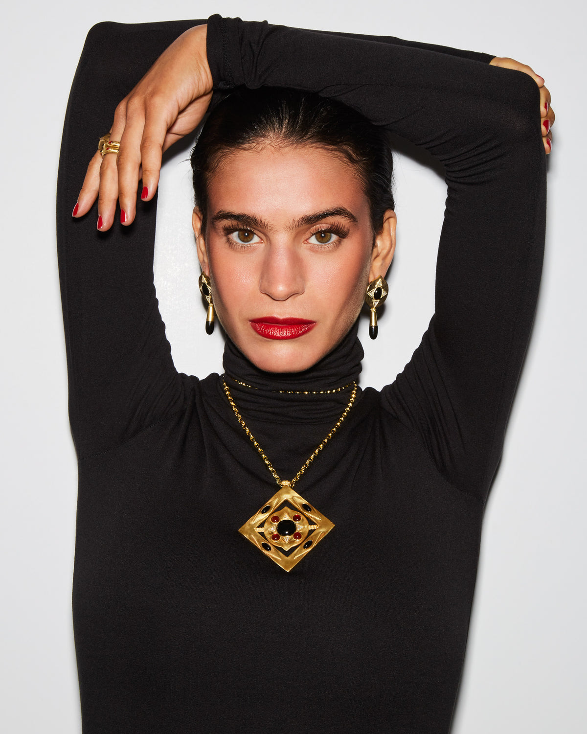 Model in a black turtleneck wearing the Hathor Teardrop Earrings in black onyx with the Hathor Spinning Pendant Necklace #color_Black Onyx