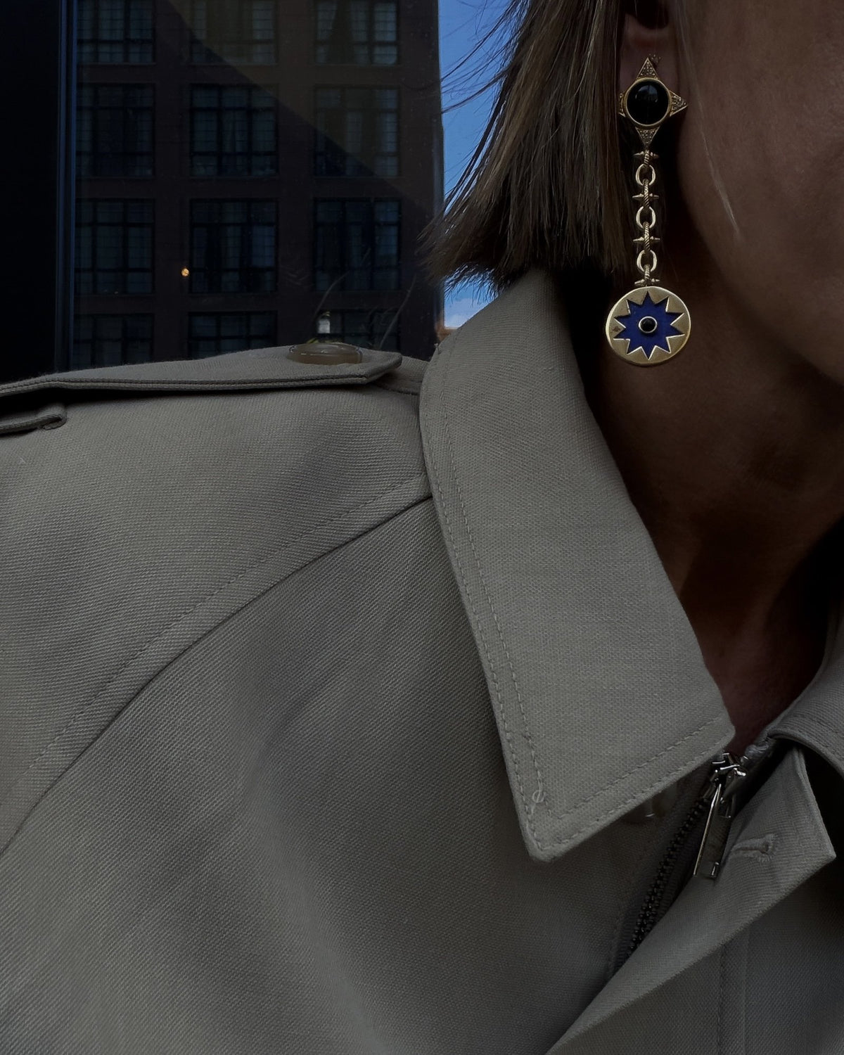 Sunburst Drop Earring in lapis against a trench coat collar