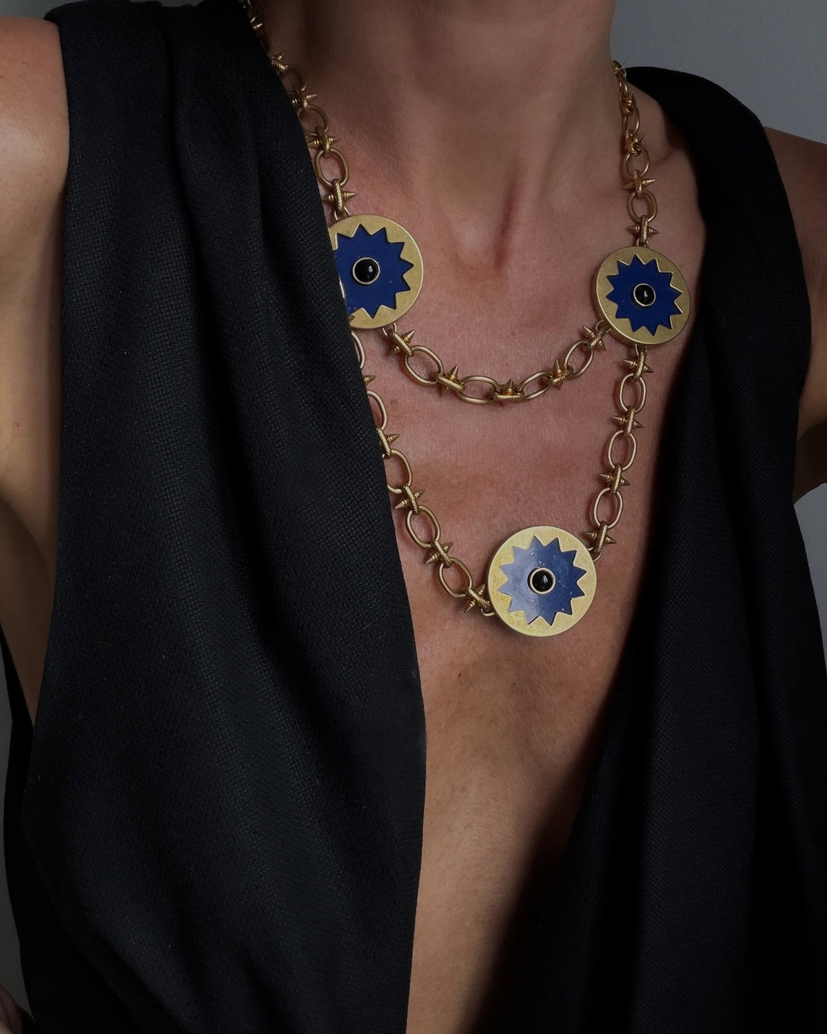 Sunburst Layering Necklace worn over the Sunburst Pendant Necklace with a black V-neck