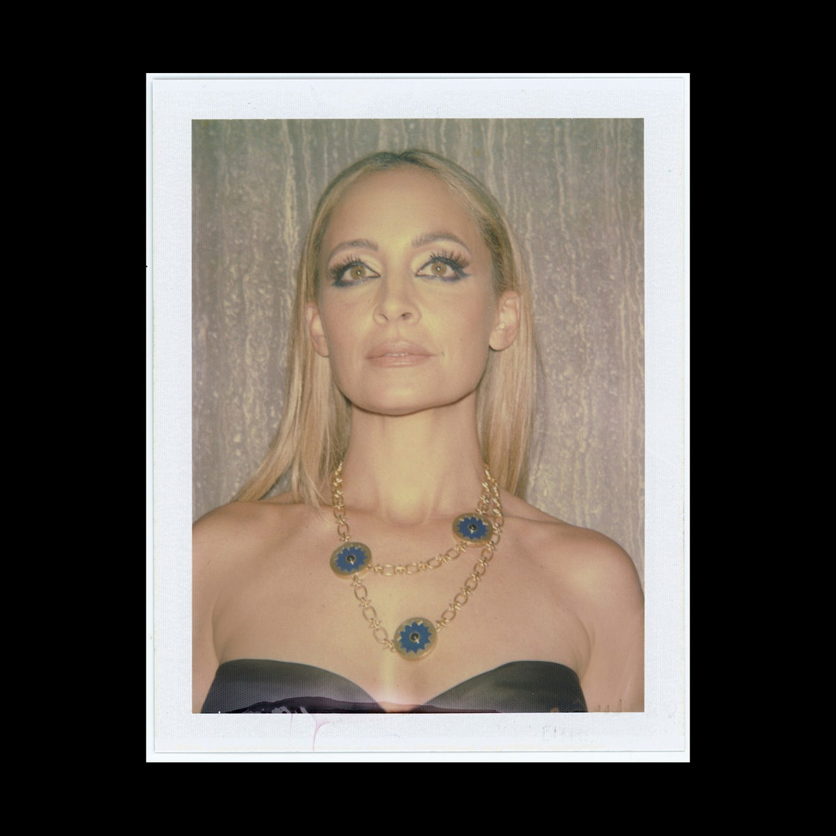 Polaroid of Nicole Richie wearing the Sunburst Layering Necklace in blue lapis, on black