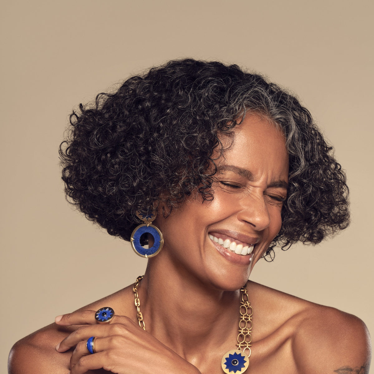 Model laughing in the Sunburst Layering Necklace in blue lapis with the Sunburst Statement Earrings and Cocktail Ring #color_14k Gold Plated Sterling Silver