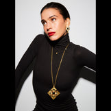 Model wearing the Hathor Spinning Pendant Necklace at full length over a black turtleneck
