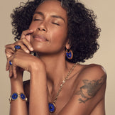 Model wearing the Sunburst Huggie Earrings in blue lapis with the Sunburst Statement Bracelet and Cocktail Ring