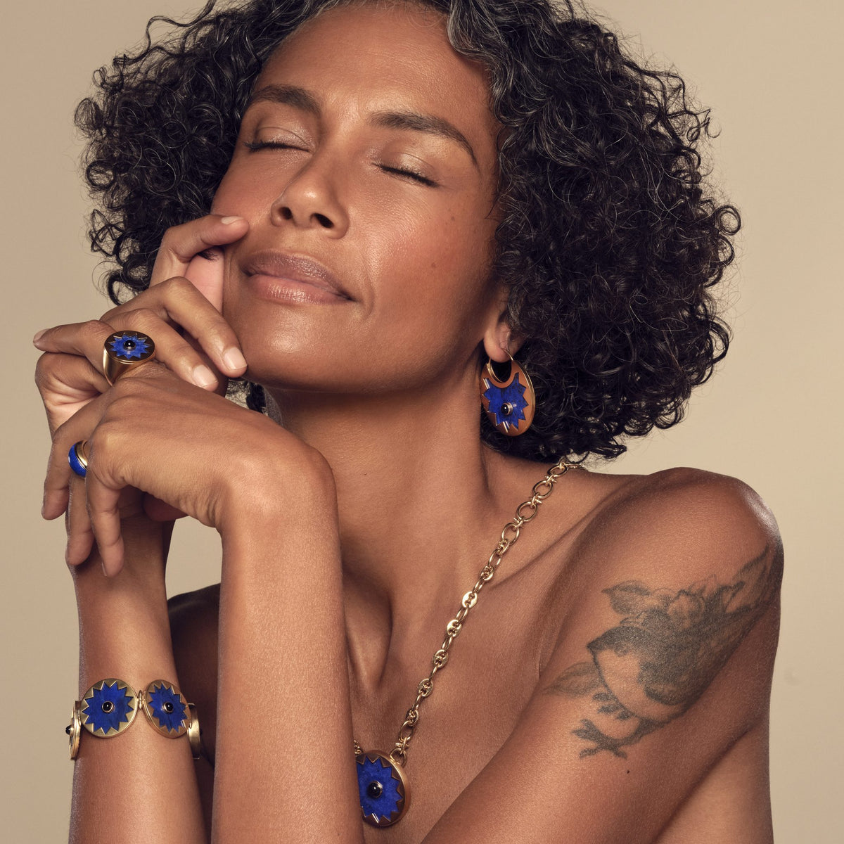 Model wearing the Sunburst Huggie Earrings in blue lapis with the Sunburst Statement Bracelet and Cocktail Ring