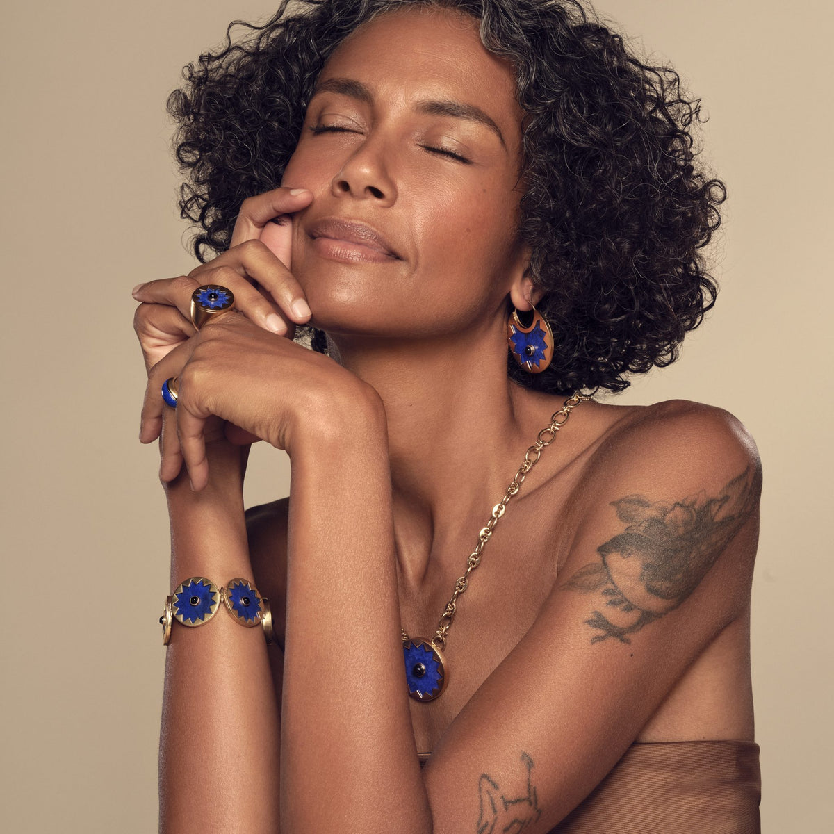 Model wearing the Sunburst Pendant Necklace in blue lapis with the Sunburst Statement Bracelet and Cocktail Ring #color_14k Gold Plated Sterling Silver