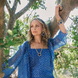 Nicole Richie in a blue dress in a tree wearing the Sunburst Pendant Necklace and Statement Earrings in blue lapis